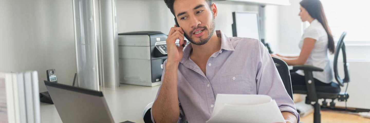 Male executive assistant taking a call in the office.