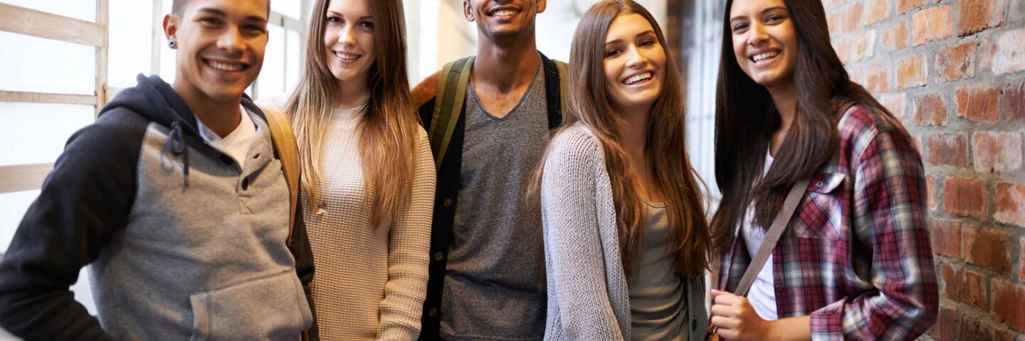 Portrait of a group of students standing in a college hallway