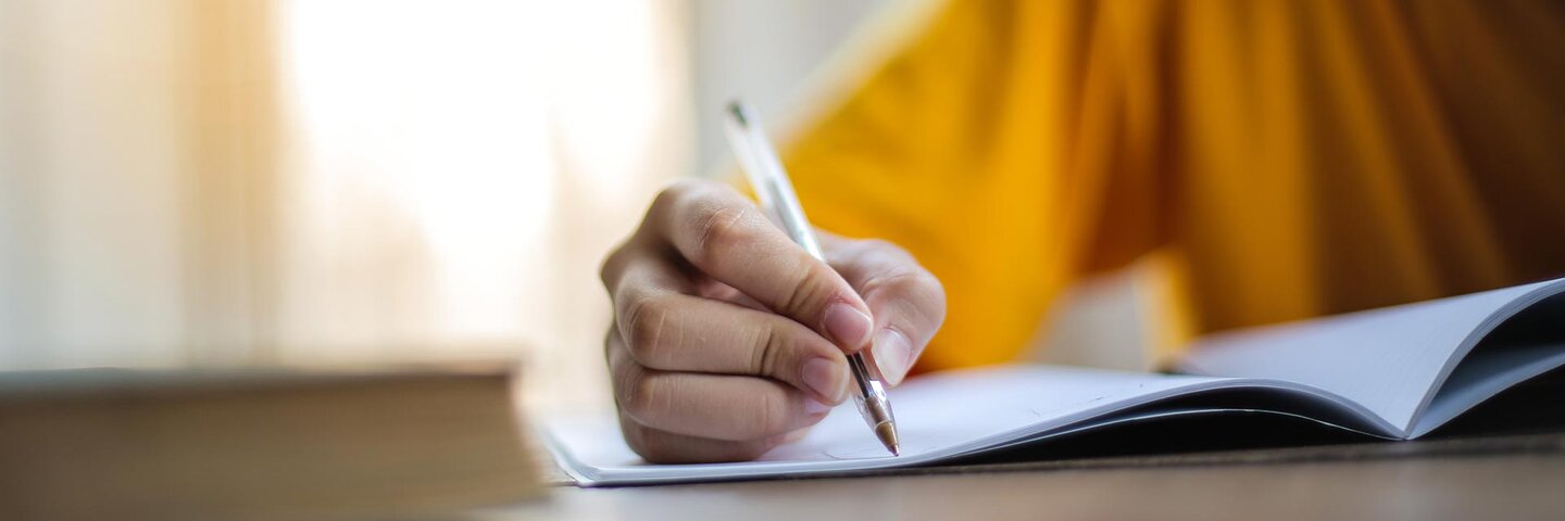 writer in yellow shirt holding pen to paper
