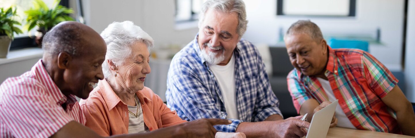 Four seniors looking at a laptop