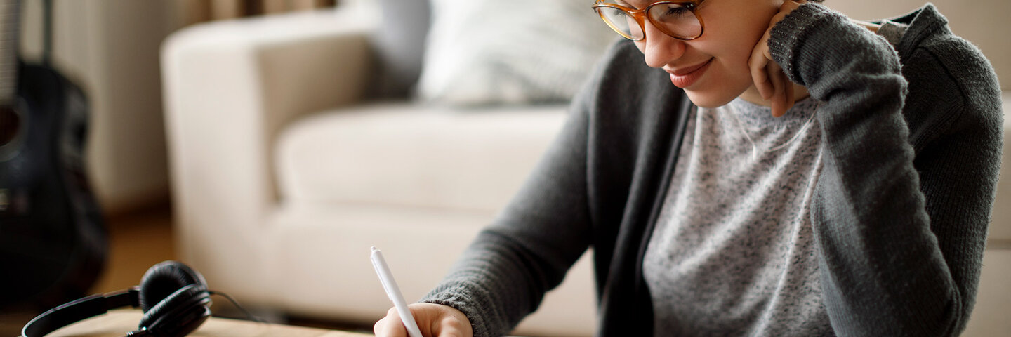 Woman writing at her desk, smiling