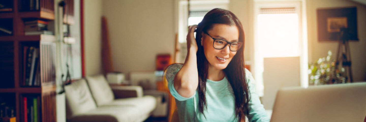 smiling woman with glasses on a laptop