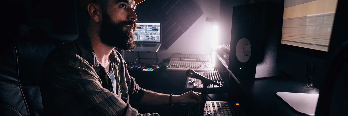 smiling male music producer using computer