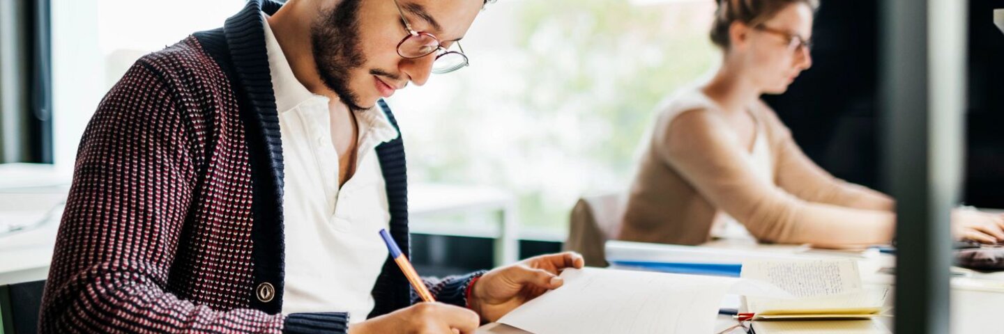 Young Student Concentrating While Studying In Public Library