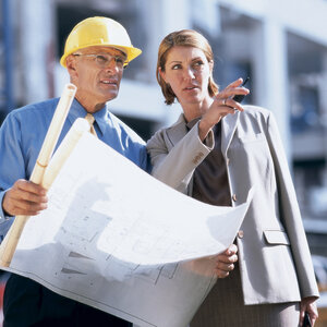 man in hard had show blueprints to a women in a suit jacket