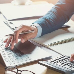 man's hands using a laptop and calculator