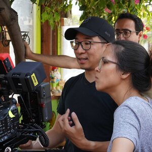 two people next to a film camera discussing film direction